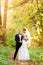 Bride and groom embrace in autumn forest