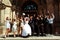 Bride, groom and friends jump in the front of a big door of the