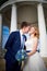 Bride and groom in gazebo near the white columns in a sunny summer day in the city park