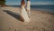 The bride and groom go barefoot on a sandy beach next to the blue ocean. They are holding hands. Happy together