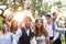 Bride, groom, guests posing for the photo at wedding reception outside in the backyard.