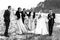 Bride and groom with happy groomsmen and bridesmaids having fun and laughing and popping champagne, black and white