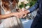 The bride and groom hold each other\'s hands at the wedding ring