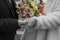 Bride and groom hold hands in a black and white colorful bouquet of roses.