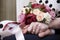 Bride and groom hold hands,  bride  bouquet of maroon and white roses,  flowers