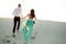 Bride and groom hold hands and run on sand in desert. Back view.