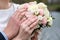 Bride and groom holding bridal bouquet of roses together. Wedding rings on a fingers