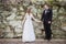 Bride and Groom holding hands in front of rock wall