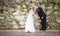 Bride and Groom holding hands kissing in front of rock wall