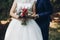 Bride and groom holding rustic bouquet of roses and succulents,