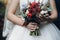 Bride and groom holding rustic bouquet of roses and succulents,