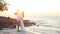 Bride and groom hug against backlight at beach at dawn