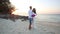 Bride and groom hug and laugh at sand beach at dawn