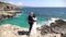 The bride and groom hug on a rocky seashore and look at the horizon