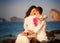 Bride and groom kiss on rock at beach