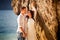 Bride and groom lean against rock