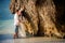 Bride and groom lean against rock