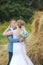 Bride and groom near hay on a rural field. Kiss of newlyweds.