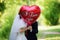 The bride and groom in the Park with the red balloon with the words \