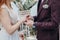 the bride and groom put on each other rings, a burgundy suit and a beige wedding dress, cloudy day, a ceremony by the sea