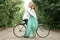 Bride and groom sit on bicycle on forest road, embrace and laugh