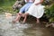 The bride and groom sitting on the shore of the lake. Foot splashing in the water.