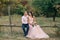 The bride and groom are sitting on a wooden fence near the ranch. The wedding in autumn is stylized in pink tones. The
