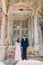 Bride and groom smiles standing in an old ruined brick window of ancient building