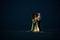 Bride and groom stand, hold hands and look at each other in desert next to garland of light bulbs at night.