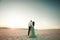Bride and groom stand on sand in desert at sunset and embrace. B