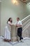 The bride and groom stand on the stairs and look lovingly at camera. Lush, charming bride on the stairs