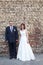 Bride and groom standing against brick wall