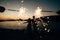 the bride and the groom standing on the on the beach of the Mamula island and holding sparklers at the sunset