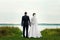 Bride and groom standing in front of the lake and looking into the distance in the direction of the park Valentine`s Day