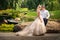 The bride with the groom in the summer on the background of textural greenery and the lake. Loving wedding couple in the city of D