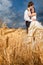 Bride and groom in tender hugs in wheat field with dramatic sky