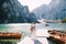 The bride and groom walk along a wooden boat dock at the Lago di Braies in Italy. Wedding in Europe, on Braies lake