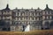 Bride and groom walk along the yellow lawn in the front of an old ruined castle