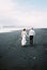 Bride and groom walk on the black sand. Vik Beach, Iceland