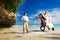 Bride and groom walking with horse on a tropical beach