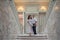 Bride and groom in wedding costumes stand on the stairs in the wedding palace