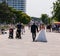 Bride and groom in wedding gown and tuxedo walk past a couple with two children in strollers on the sidewalk in this tourist town