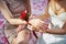 Bride helps to tie flower rose on hand of her bridesmaid