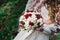 Bride hold in hand wedding bouquet of biege and red roses.