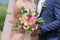 Bride holding a beautiful bridal bouquet. Wedding bouquet of peach roses by David Austin, single-head pink rose aqua, eucalyptus,