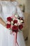 The bride is holding a bouquet of the bride from large red roses, small pink roses and white lilies