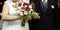 Bride holding bouquet of flowers with her father at the entrance of religious ceremonial