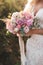 Bride holding in hands small wedding bouquet in pastel colors