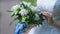 The bride is holding a large beautiful wedding bouquet in her hands, touching the flowers in it, fingering them with her