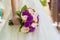 Bride holding violet wedding carnation bouquet against gown